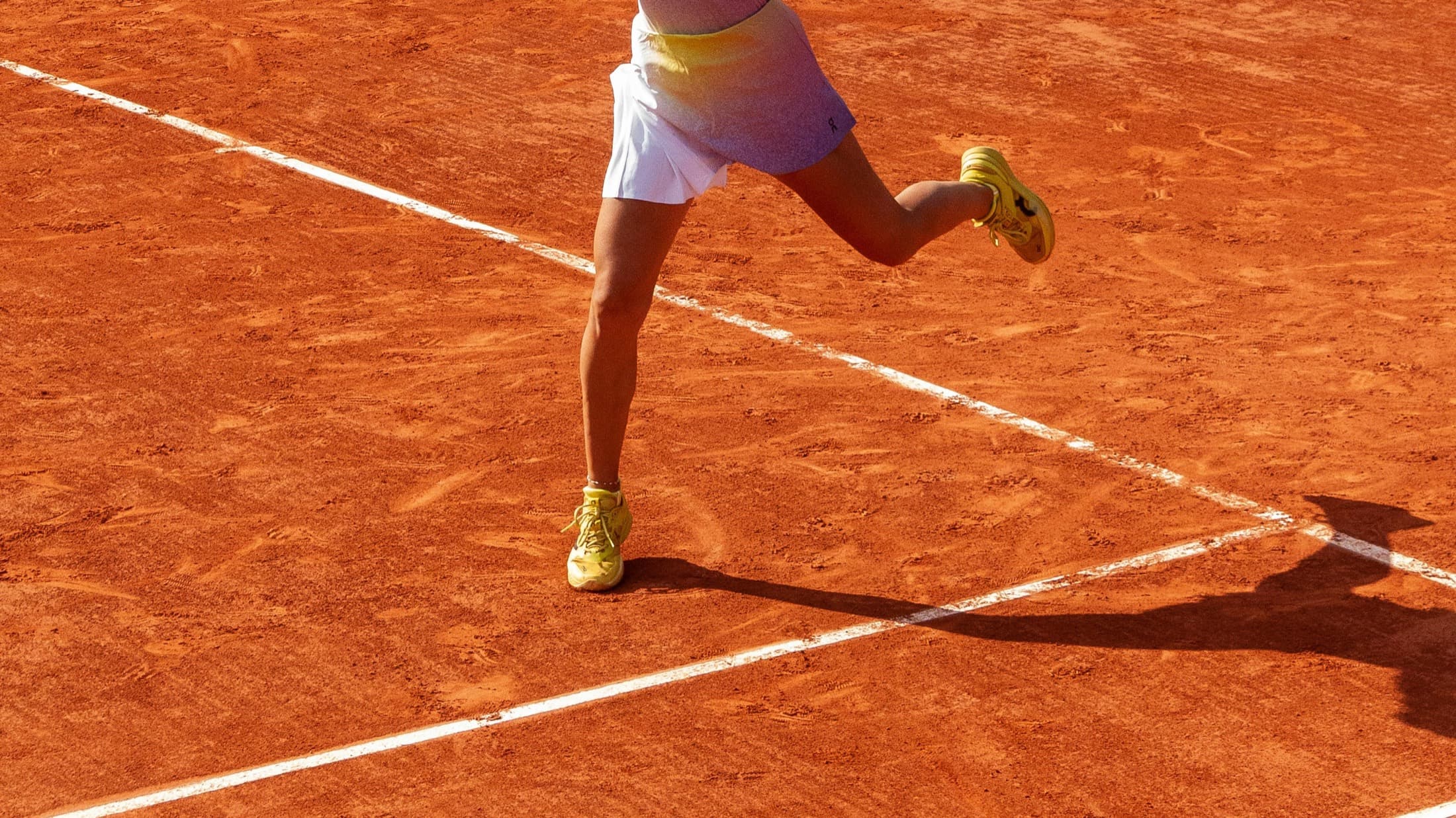 Player mid-stride chasing a ball across the red clay